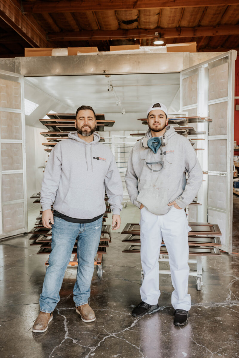 Two Rojas Painting team members in the cabinet spray booth