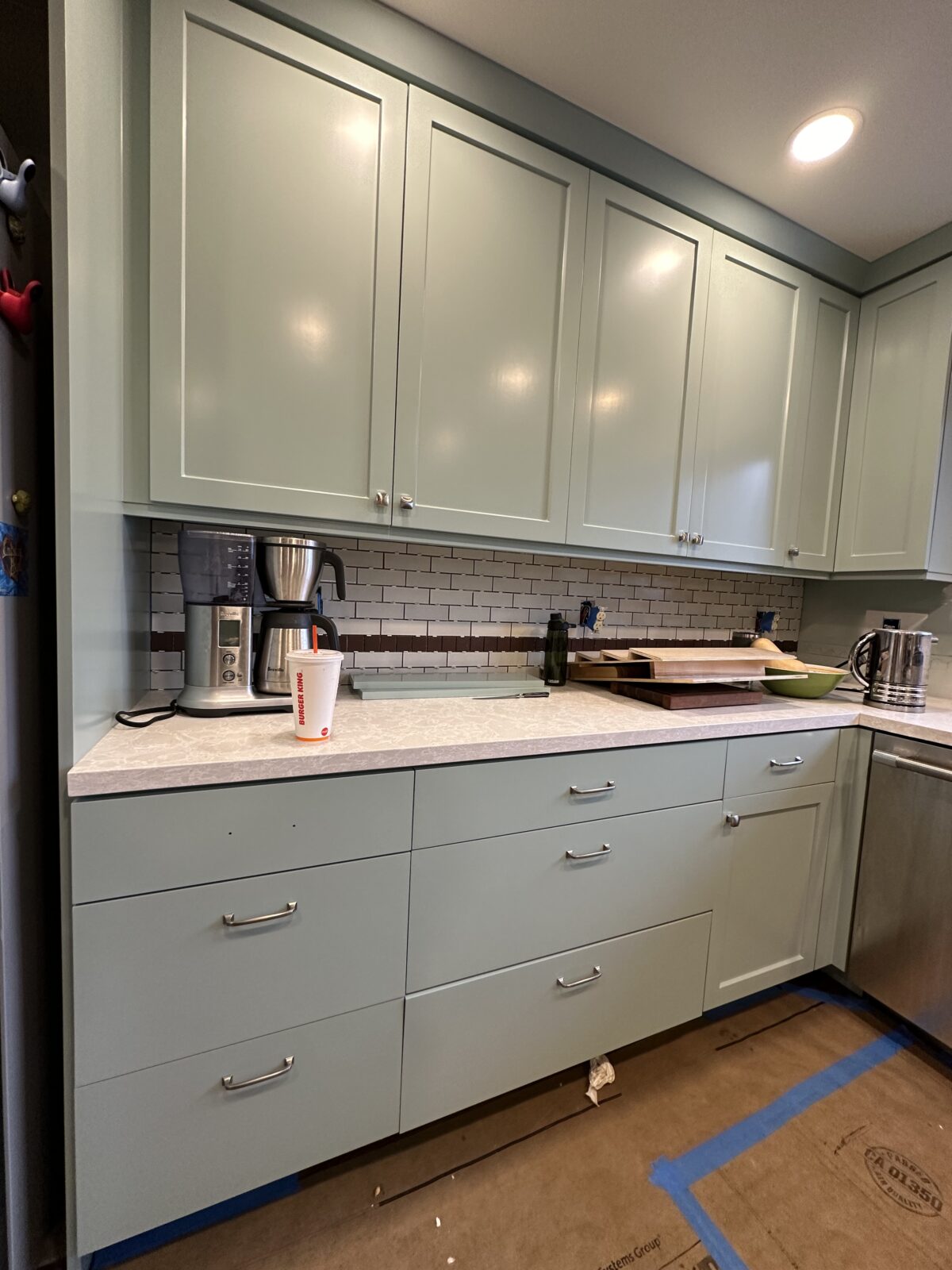 Sage green painted shaker cabinets with a subway tile backsplash