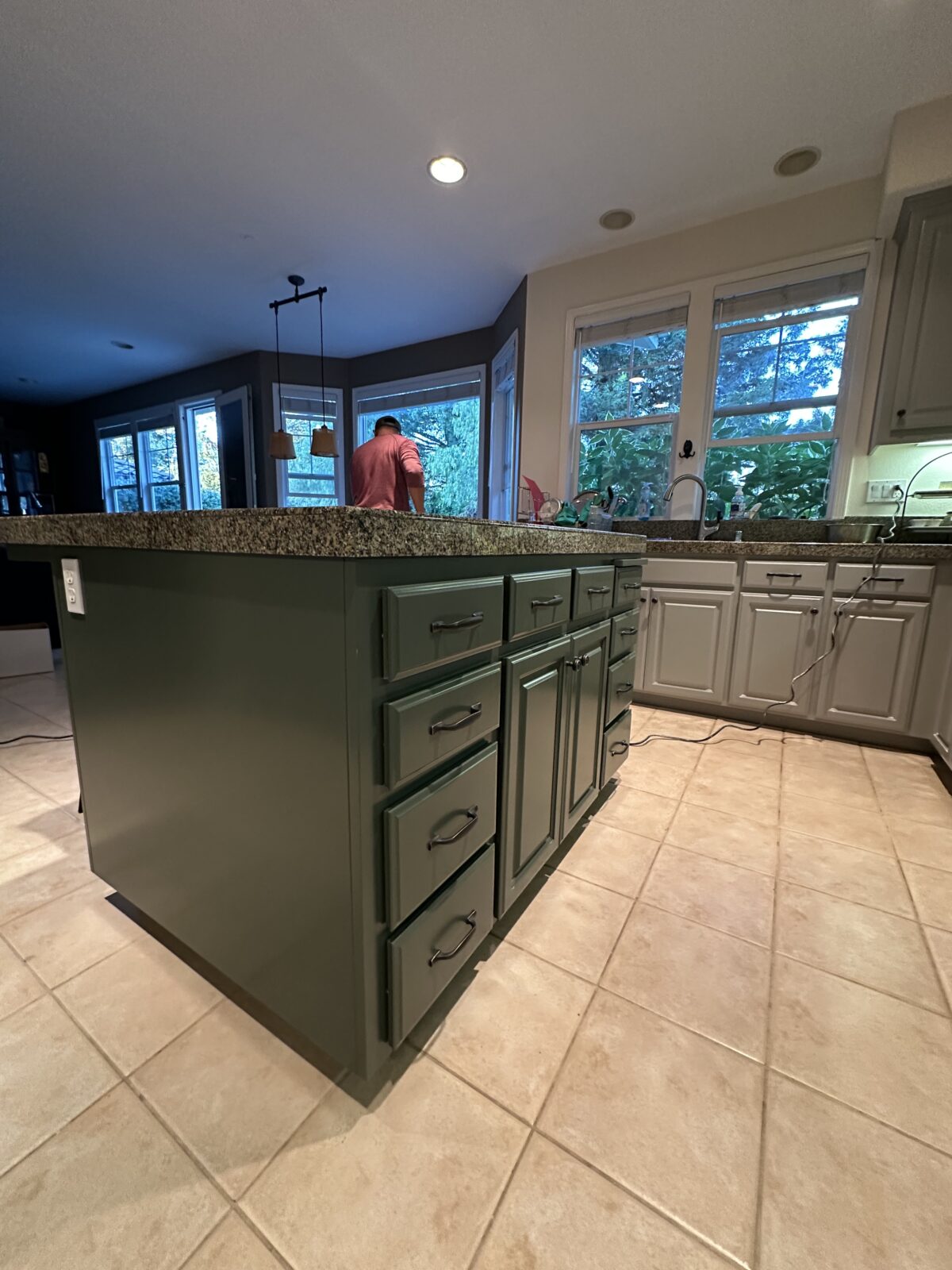 Kitchen island painted deep green with gray perimeter cabinets