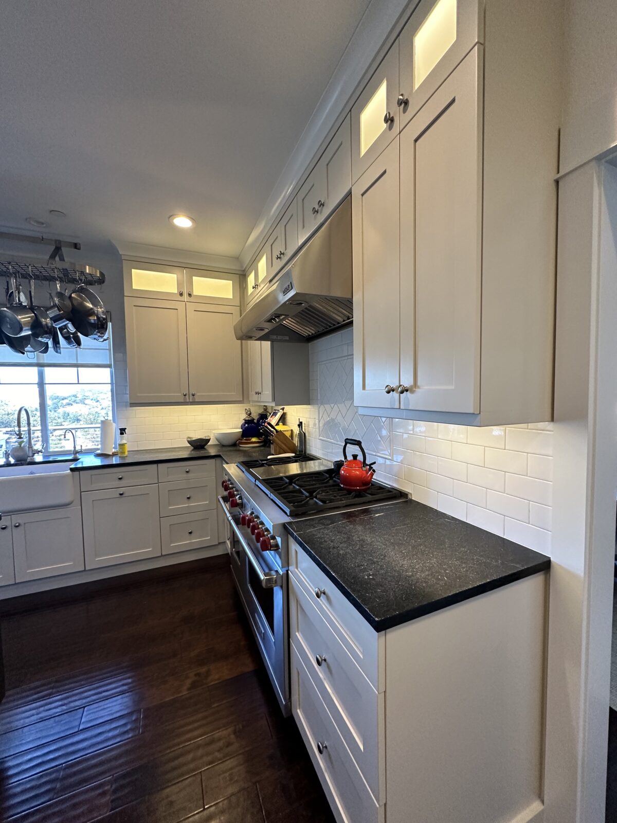 White painted kitchen cabinets with dark counters and a range